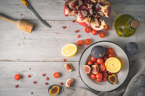 A wooden table with a colorful bowl of food and fresh ingredients